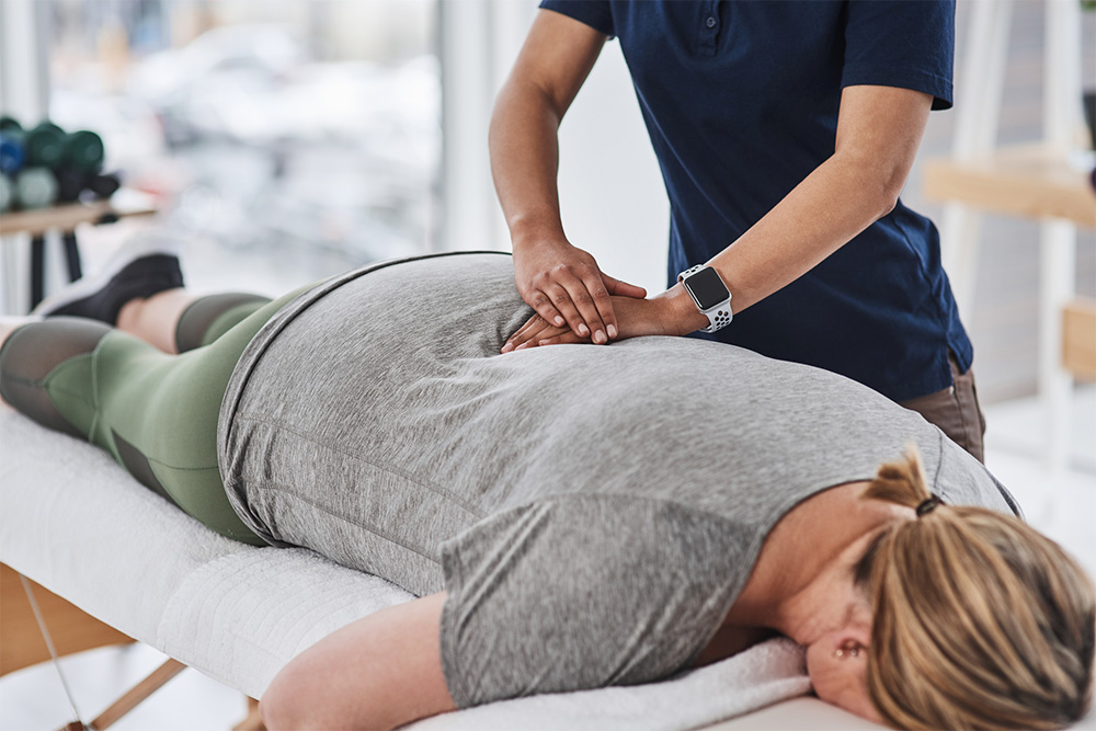 Physical therapist helping patient with lower back pain.