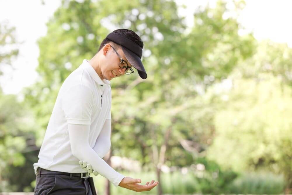 Male golfer grabbing his elbow in pain.