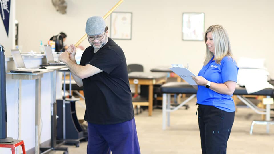 Patient performing golf stretches in a physical therapy clinic.