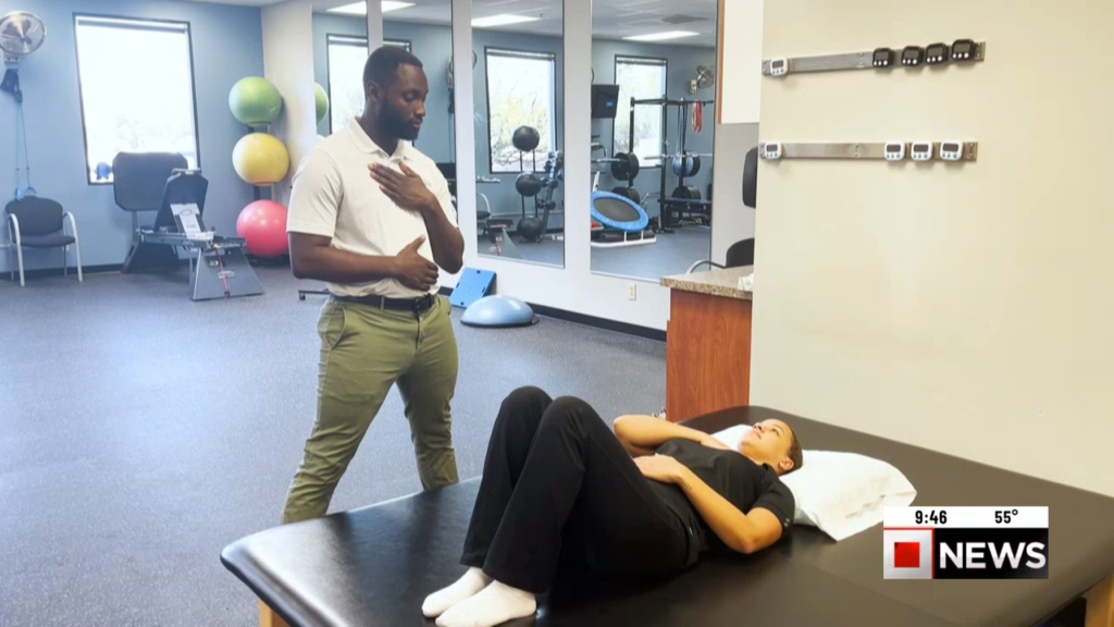 Physical Therapist working with patient laying on her back stretching.