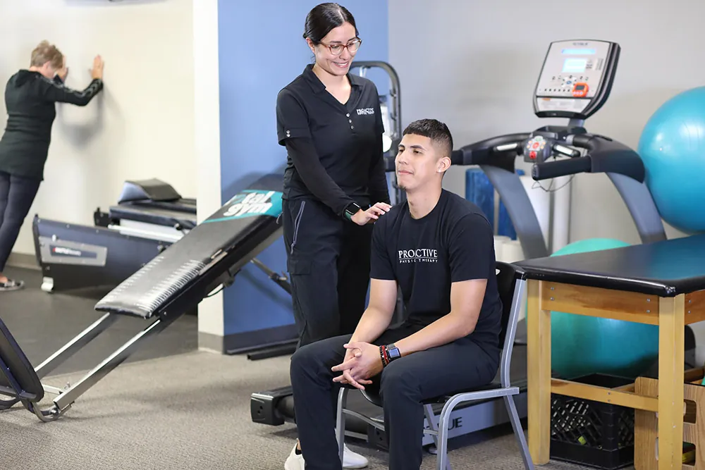 Therapist helping patient that is sitting in a chair.