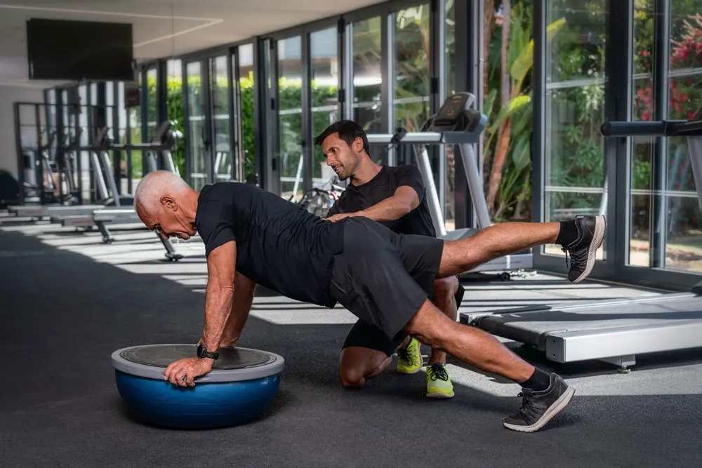 Older man doing exercises for balance on a gymnastic ball.