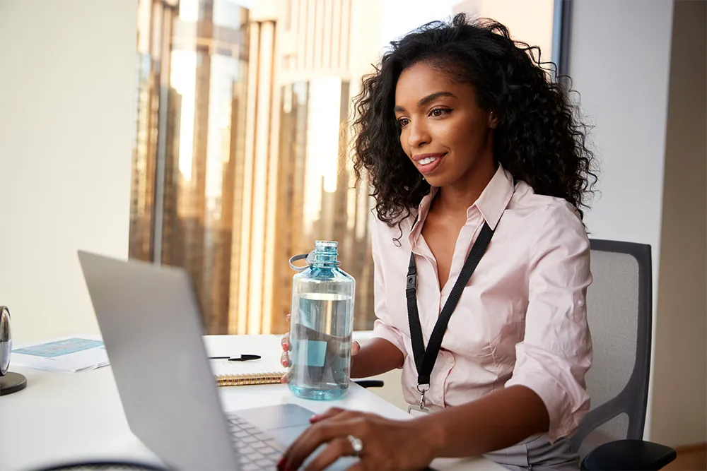 Woman drinking water in while working.