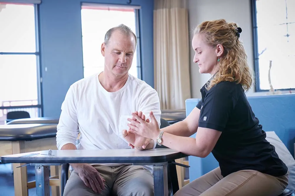 PT, working with patient performing hand exercises.