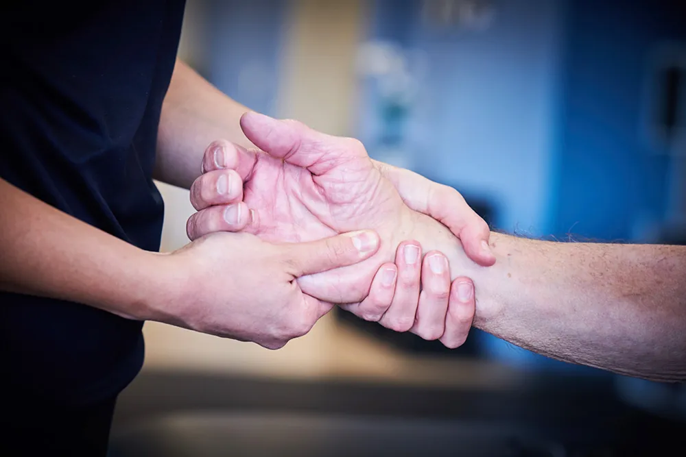 PT, performing therapy to patient's hand.