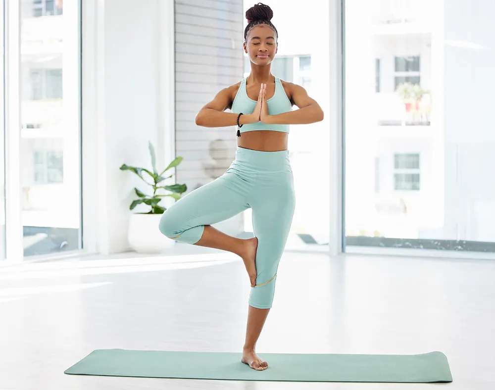 Woman standing on one foot while having eyes closed.