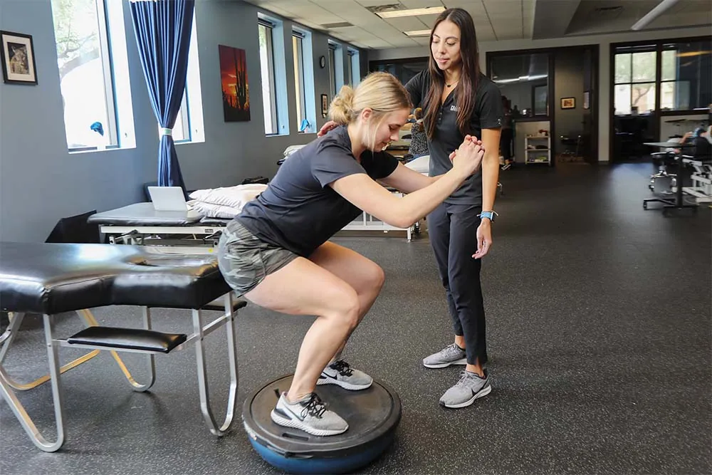 PT, Alicia helping patient stand on balance ball.