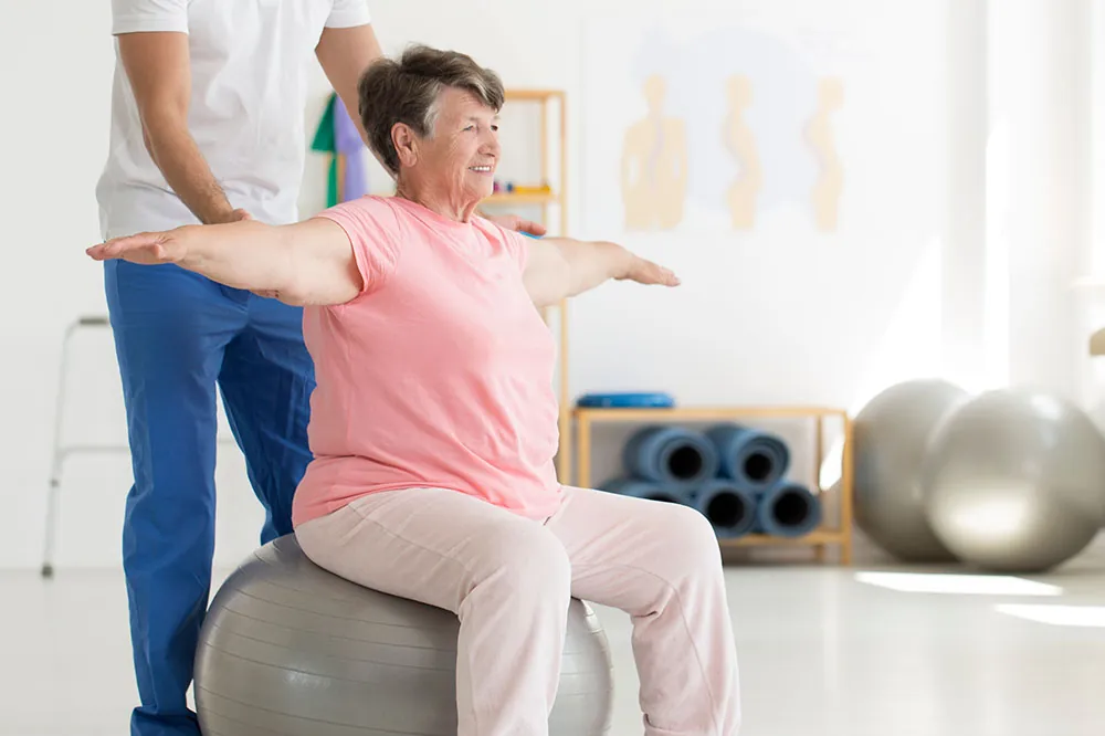 PT assisting patient while balancing on ball.