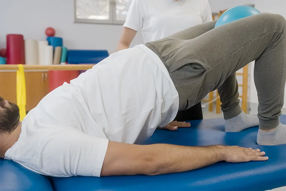 Man holding ball in between legs to strengthen pelvic floor.