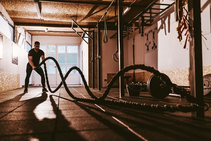 Athlete performing rope slams inside the gym.