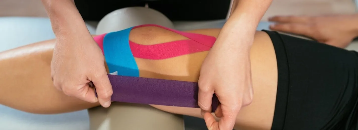 Physical therapist Kinesio taping a patients knee.