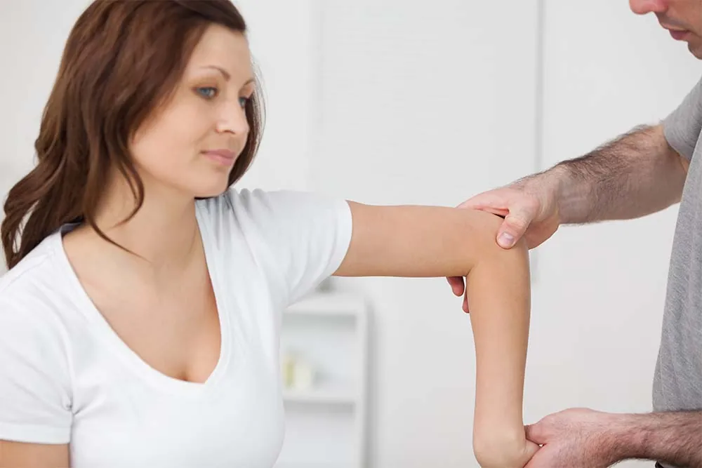 Physical therapist treating woman's elbow pain.