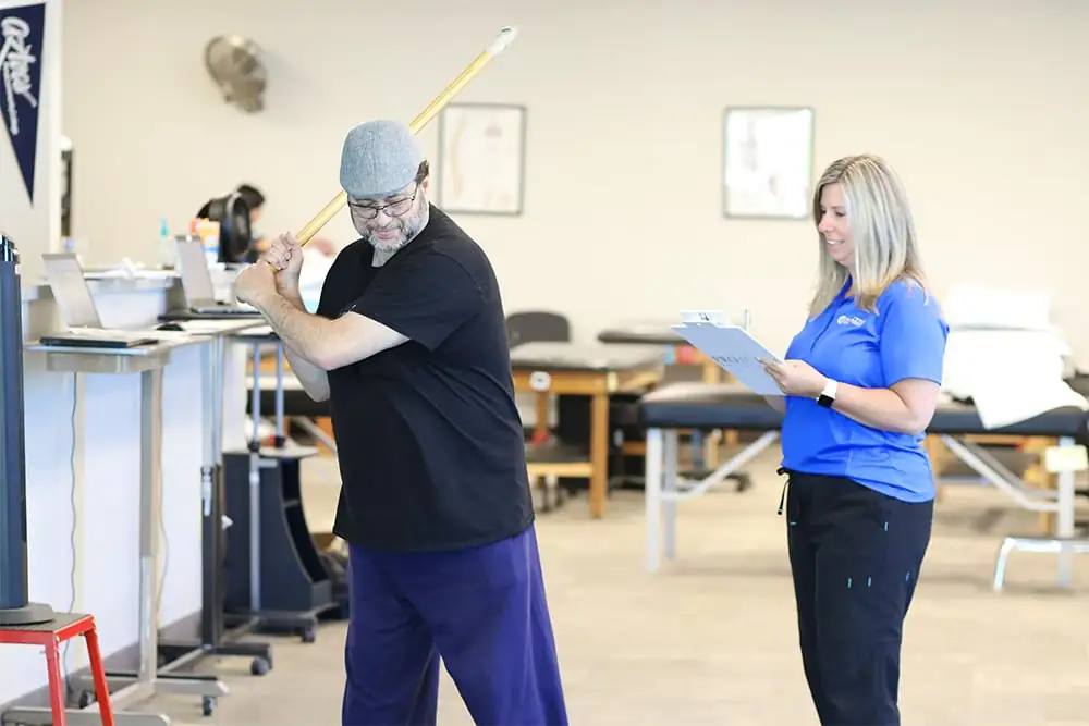 Patient performing golf stretches in a physical therapy clinic.